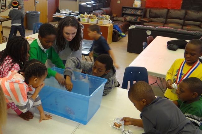 A student from the class "Service with Youth in STEM" interacts with elementary school children at an after-school science club.