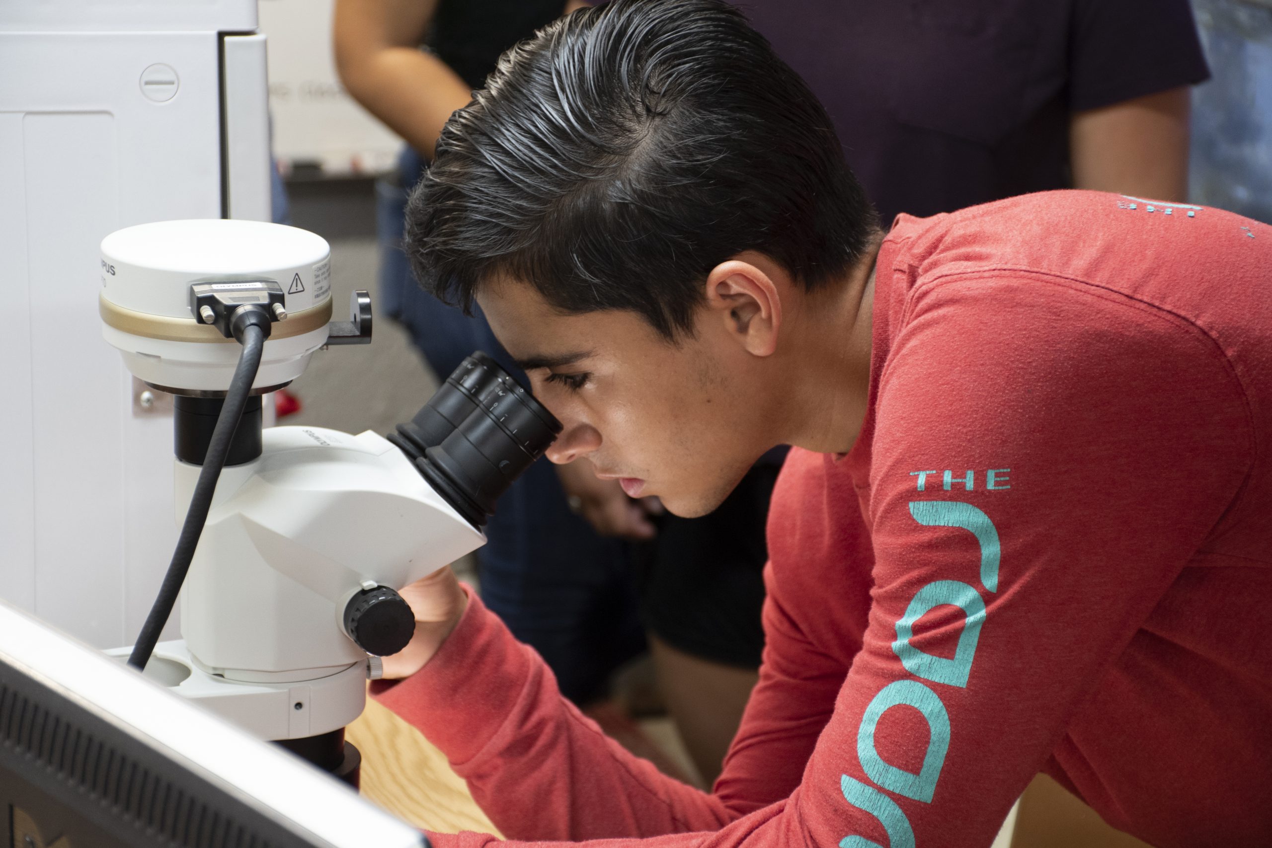 A student looks at a microscope. 