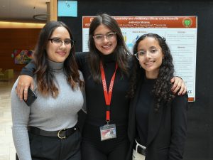 Three summer research program students pose together after presenting their research at a poster session.