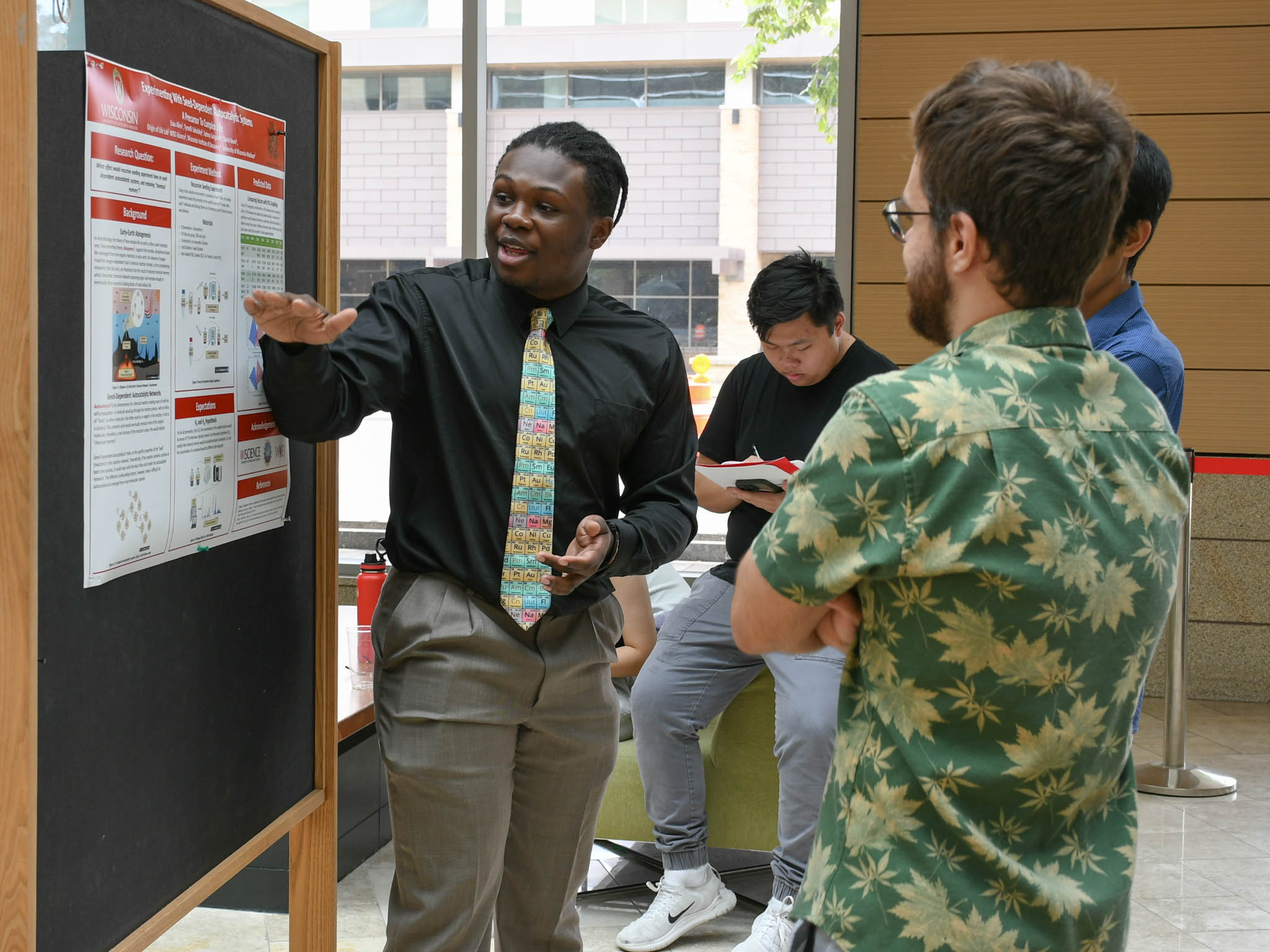 BI student Esau Allen explains his research poster to onlookers.