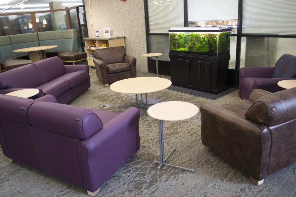 Several couches and lounge chairs with tables and a fish tank in the BioCommons.