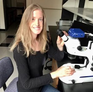 Claire Richardson sits at a microscope in the lab.