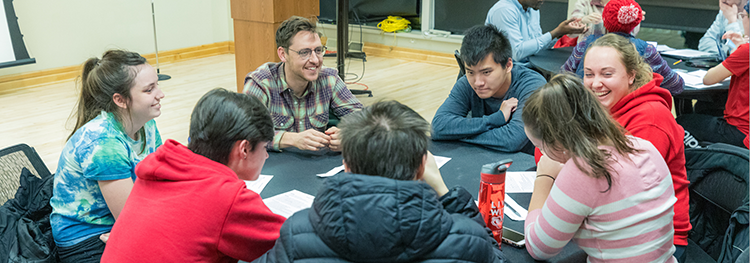Several students and a mentor are gathered around a table during a BioHouse Seminar.