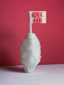 A white 3D printed object representing a fungus spore with a flag on top that reads "Hull Lab" in red letters. 