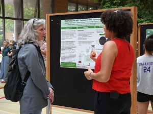 Student Meredith Aiyenero stands in front of her poster at the CMBS Poster Fair, explaining her research to Janet Branchaw, Director of WISCIENCE.