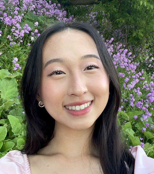 Headshot of Alysson Lee with a background of pink wildflowers.
