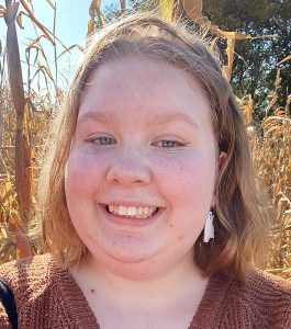 Headshot of Charlotte Knihtila with a background of dried cornstalks.