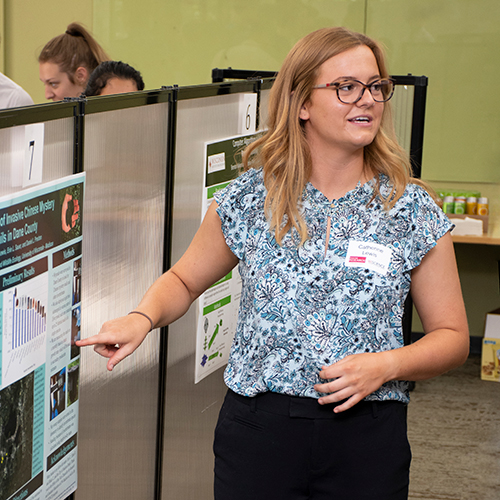 A student at a poster fair presents her poster.