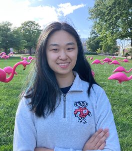 Headshot of Stephanie Zhang. Behind her is UW-Madison's Bascom Hill, which is filled with plastic flamingos.