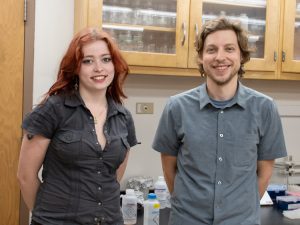 Eleanor Ford, a summer research program student, and her mentor, Zach Farrand, stand together smiling in a lab. 