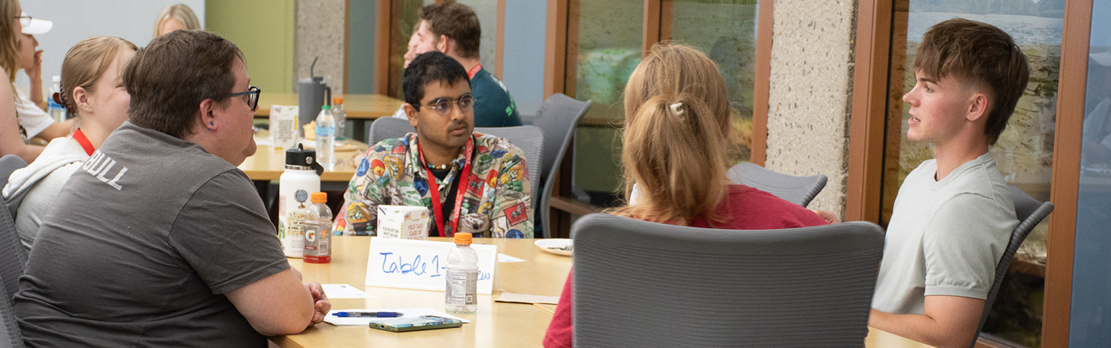 Several students sit around a table and talk.