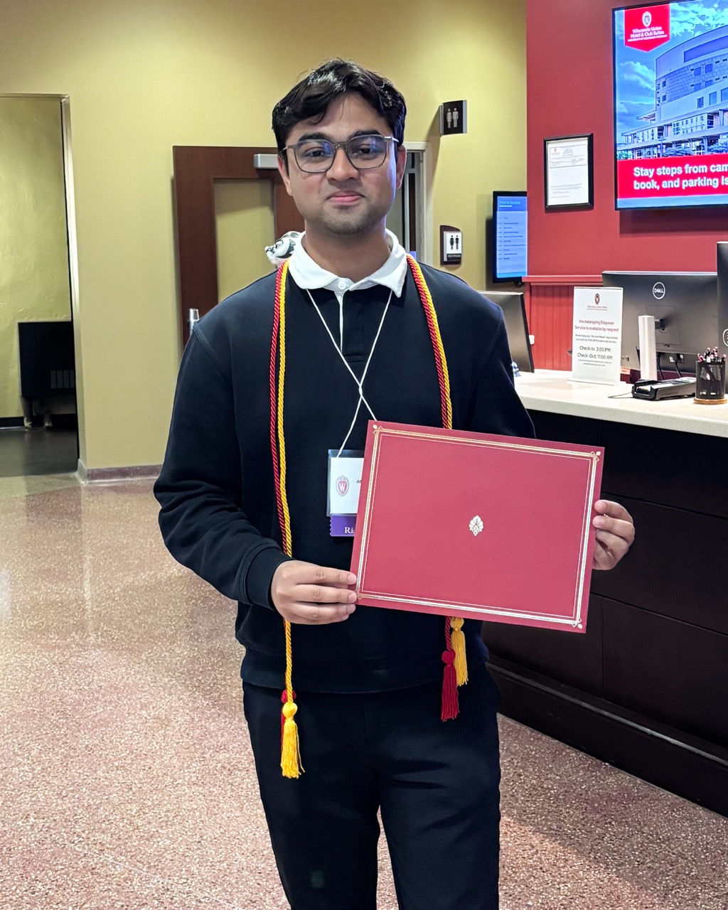 A student smiles while holding a folder containing his Leadership Certificate.