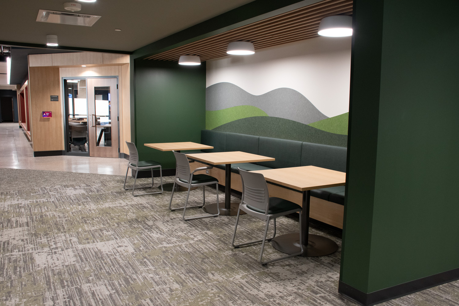 Chairs, booths, and tables in an open area with a classroom door in the background.