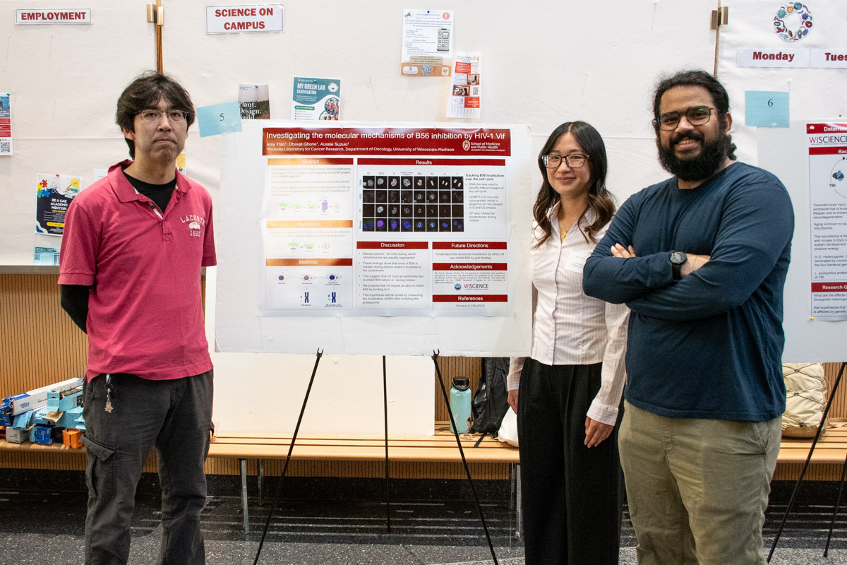 A student, her mentor, and her lab PI stand next to a research poster, smiling.
